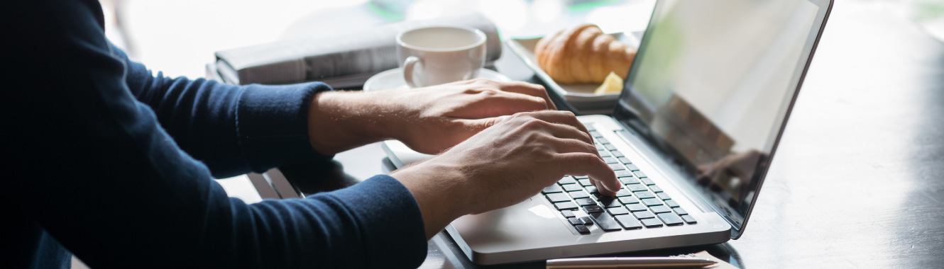 A person typing on computer at coffee shop