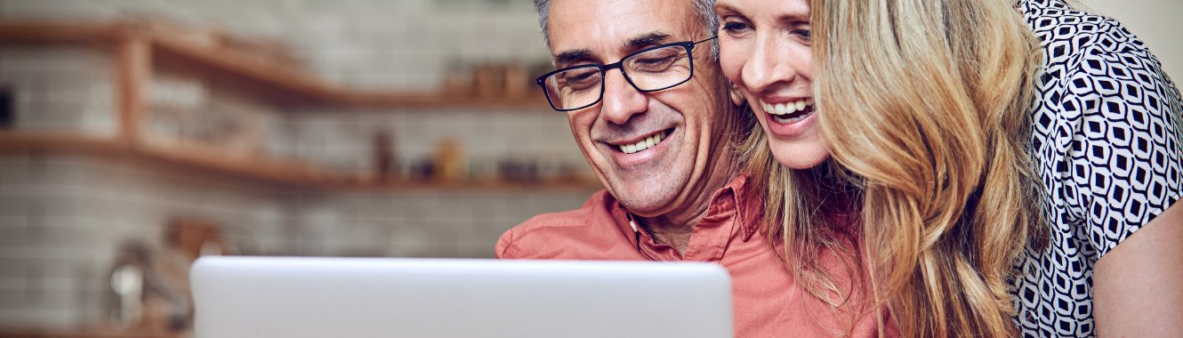 Mature man and woman looking at a laptop and smiling.