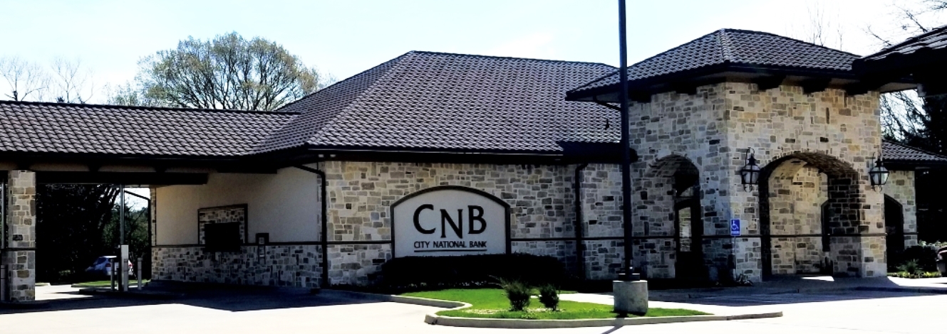 Large white and brown stone building with large arched entry.