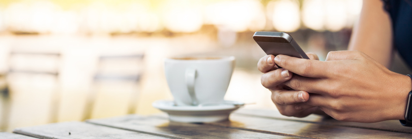 Person using mobile phone with coffee