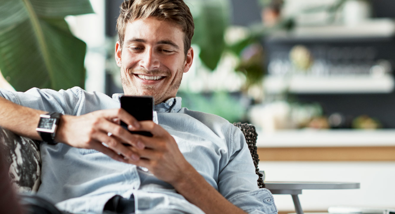 A man looking at his mobile phone and smiling