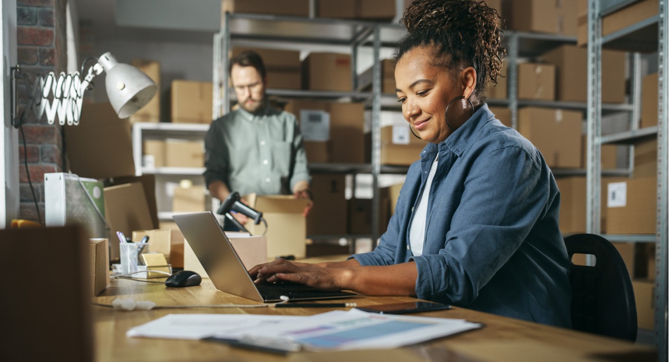 diverse male and female warehouse inventory managers talking using a laptop computer